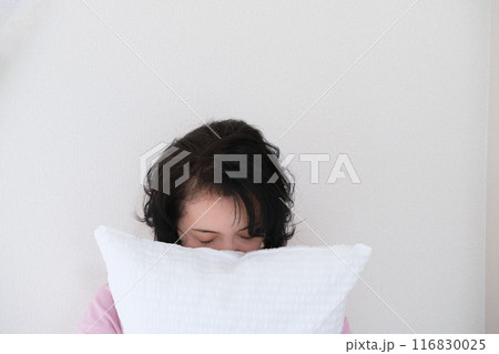 枕を抱えて心を体を整えるミドル女性 116830025