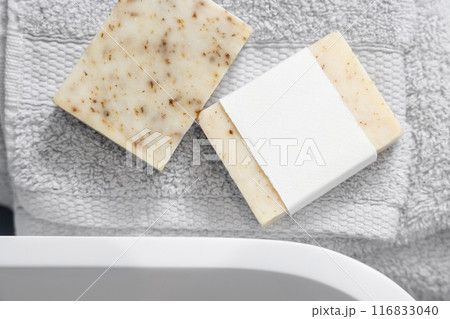 Soap bars with blank label on light grey towels near vessel sink in bathroom closeup, mockup 116833040