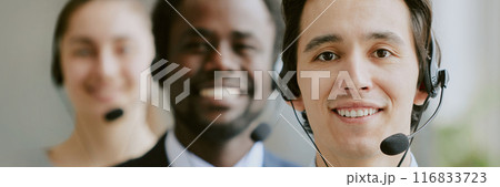Website header of biracial team of operators wearing black headphones with microphone, thy looking at camera and smiling Website header of biracial team of operators wearing black headphones with microphone, thy looking at camera and smiling 116833723