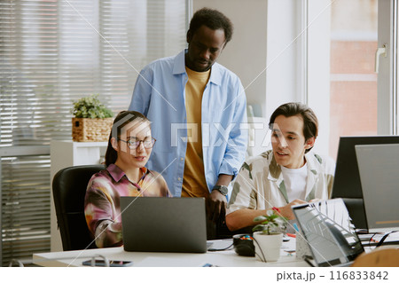 African American teamlead standing between two Caucasian coworkers who showing new project to him African American teamlead standing between two Caucasian coworkers who showing new project to him 116833842
