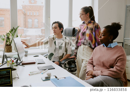 Young Caucasian programmer showing presentation to his biracial coworkers at work in light spacious IT office Young Caucasian programmer showing presentation to his biracial coworkers at work in light spacious IT office 116833858