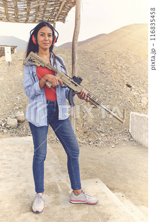 Woman empowered shooter aiming assault rifle at target. Selective Focus Woman empowered shooter aiming assault rifle at target. Selective Focus 116835458