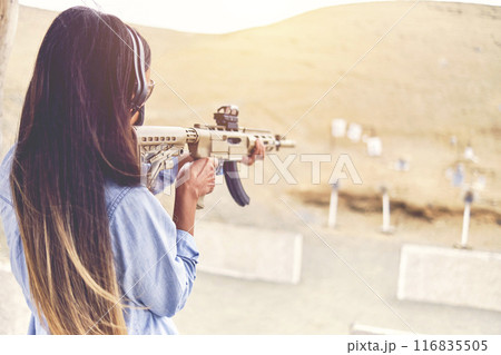 Woman empowered shooter aiming assault rifle at target. Selective Focus Woman empowered shooter aiming assault rifle at target. Selective Focus 116835505