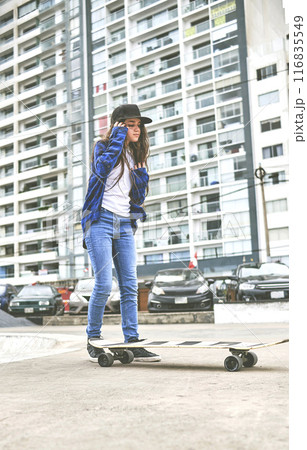 Girl having fun riding skateboards at skate park, Portrait of smiling young female skateboarder holding her skateboard. Recreational Activity Concept. 116835549