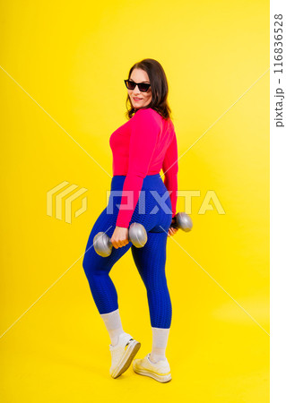 Full length isolated studio portrait of a beautiful chubby woman doing exercises with dumbbells. 116836528