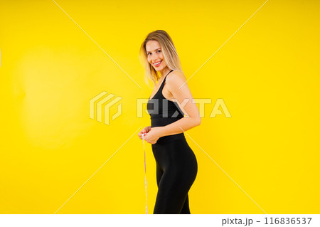 A weight loss and healthy lifestyle concept. Smiling slim woman measuring her waist with tape 116836537