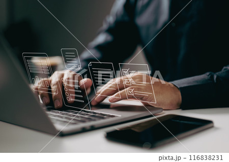 Typing on a laptop with digital documents and checklists floating above. It symbolizes the use of digital tools for task management, organization, and efficient workflow in a modern work environment. 116838231