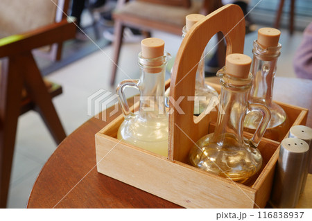 Wooden tray with condiment bottles on table in cozy cafe, creating warm inviting atmosphere Wooden tray with condiment bottles on table in cozy cafe, creating warm inviting atmosphere 116838937