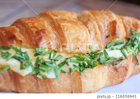 Enjoy a delectable sandwich filled with fresh herbs nestled in a flaky croissant Enjoy a delectable sandwich filled with fresh herbs nestled in a flaky croissant 116838945