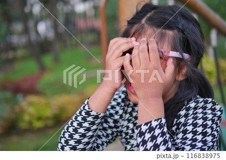 a upset child girl cover her face with hand  116838975