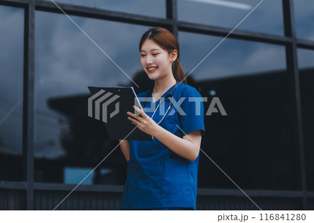 Confident nurse on her way to work in a clinic. Pretty female nurse drinking coffee and rest after hard work. The young adult female nurse drinks her coffee as she arrives to work at the hospital. Confident nurse on her way to work in a clinic. Pretty female nurse drinking coffee and rest after hard work. The young adult female nurse drinks her coffee as she arrives to work at the hospital. 116841280