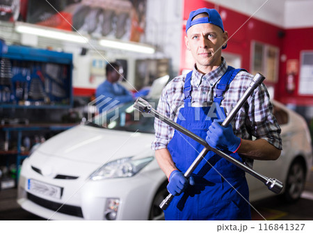Professional auto mechanic screwing the wheel 116841327