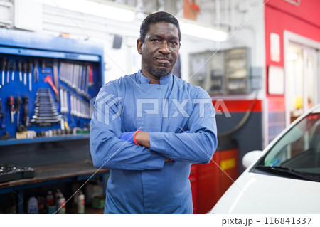 Portrait of confident mechanician posing near car at service 116841337