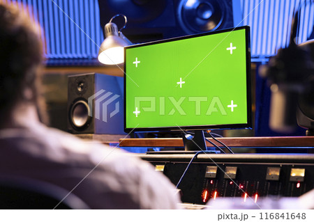 Singer and expert mixing and processing music for a new album in control room at professional recording studio, working on songs. Diverse team of artists producing a new tune. 116841648