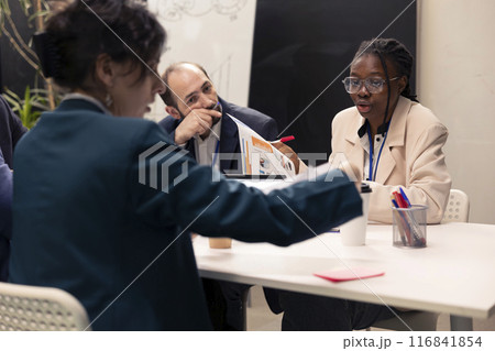 Team of colleagues working on resource allocation initiatives during a conference, making important budgeting decisions to corelate with business goals and objectives. Employees review strategies. 116841854
