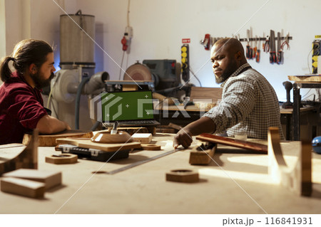 Carpenter talking with client about commissioned furniture assembling job, presenting on mockup laptop. Cabinetmaker shows customer blueprint on CAD software on green screen notebook Carpenter talking with client about commissioned furniture assembling job, presenting on mockup laptop. Cabinetmaker shows customer blueprint on CAD software on green screen notebook 116841931