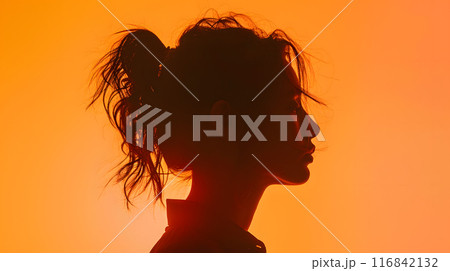 The image showcases the artistic silhouette profile of a woman with a tousled ponytail against a vibrant orange background, creating a bold and emotive artistic expression 116842132