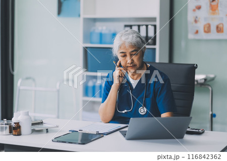 Thoughtful Hispanic female doctor sitting at her desk in a bright medical office, looking at a laptop screen. Thoughtful Hispanic female doctor sitting at her desk in a bright medical office, looking at a laptop screen. 116842362