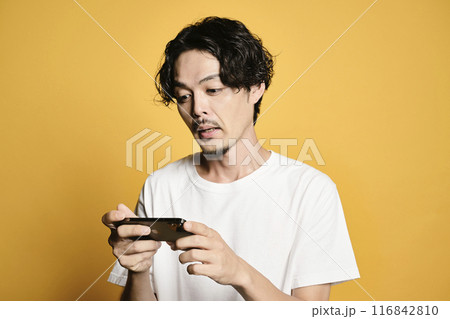 カラーバックでスマホを触る男性 116842810