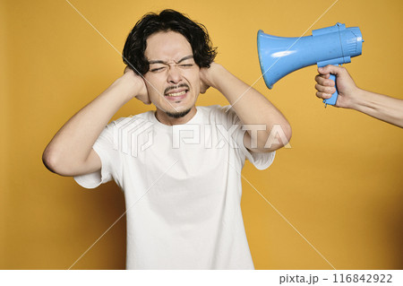 カラーバックで拡声器の音で耳を塞ぐ男性 116842922
