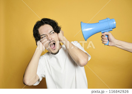 カラーバックで拡声器の音で耳を塞ぐ男性 116842926