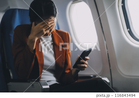 Stressed and serious young asian businesswoman remote working on the plane, suffering from headache and airsick during the flight. Stressed and serious young asian businesswoman remote working on the plane, suffering from headache and airsick during the flight. 116843494