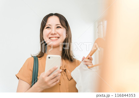 スマホを持ちながら買い物をする女性(ファッション・アパレル・ショッピング) スマホを持ちながら買い物をする女性(ファッション・アパレル・ショッピング) 116844353