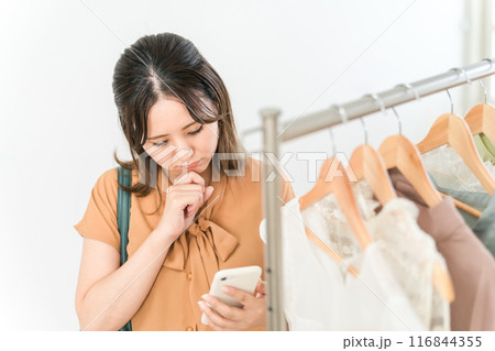スマホを持ちながら買い物をする女性(ファッション・アパレル・ショッピング) スマホを持ちながら買い物をする女性(ファッション・アパレル・ショッピング) 116844355