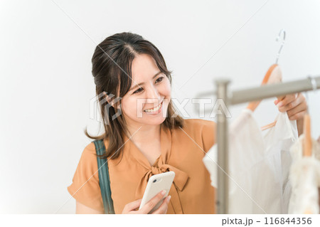 スマホを持ちながら買い物をする女性(ファッション・アパレル・ショッピング) スマホを持ちながら買い物をする女性(ファッション・アパレル・ショッピング) 116844356