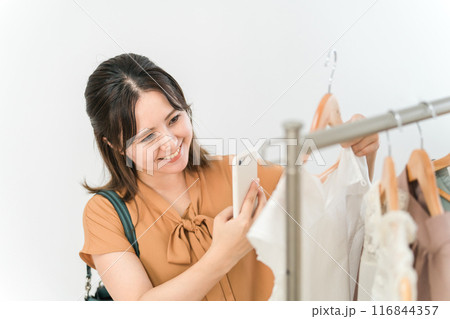 スマホを持ちながら買い物をする女性(ファッション・アパレル・ショッピング) スマホを持ちながら買い物をする女性(ファッション・アパレル・ショッピング) 116844357