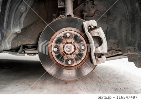 Old brake rotor and caliper with brake pad in a suspension of car Old brake rotor and caliper with brake pad in a suspension of car 116847497