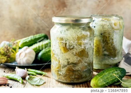 Healthy homemade fermented food. Salted pickled cucumbers with garlic, preserved canned in glass jar. Home economics, autumn harvest preservation. 116847893