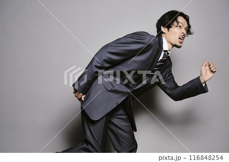 グレーバックで走り出すスーツを着た男性 グレーバックで走り出すスーツを着た男性 116848254
