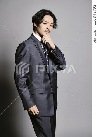 グレーバックで立つスーツを着た男性 116848792