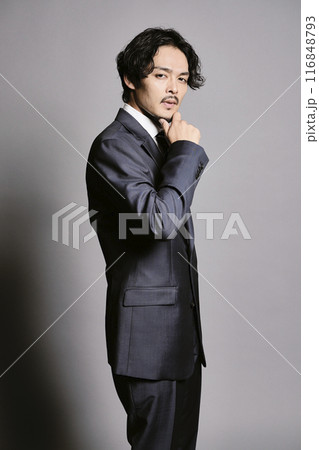 グレーバックで立つスーツを着た男性 116848793