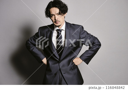 グレーバックで立つスーツを着た男性 116848842