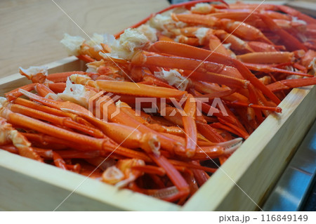 Boiled crab legs in a wooden box on a wooden table. 116849149