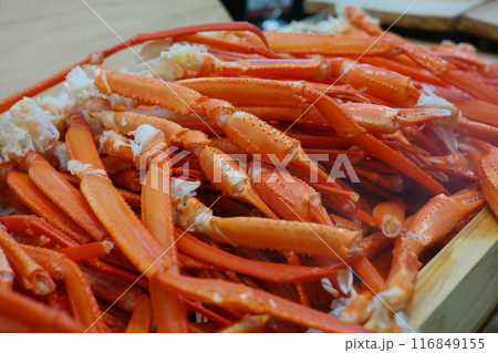 Boiled crab legs in a wooden box on a wooden table. 116849155