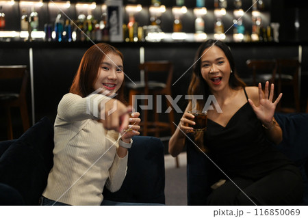 Two joyful women having a great time at a cozy bar. Nightlife, celebrations and friendship concept Two joyful women having a great time at a cozy bar. Nightlife, celebrations and friendship concept 116850069