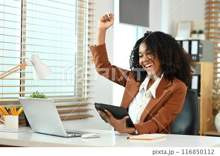 Excited African American businesswoman with gesturing yes, celebrating her achievement at office desk Excited African American businesswoman with gesturing yes, celebrating her achievement at office desk 116850112