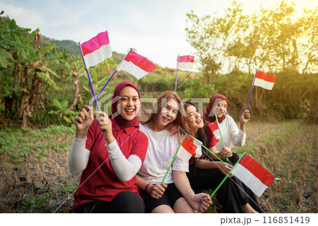 Portrait group of women with excited expressions holding small Indonesian flag 116851419
