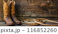 Fancy cowgirl boots with a cowboy hat and lasso rope background a wooden wall 116852260