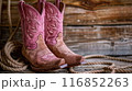 Fancy cowgirl boots with a cowboy hat and lasso rope background a wooden wall 116852263