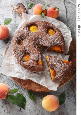 Chocolate cocoa pie with fresh peaches close-up on wooden board. Vertical top view 116852879