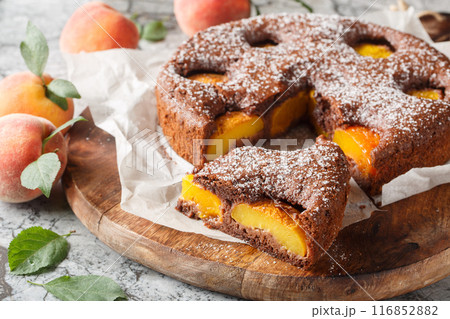 Delicious cocoa peach brownie or chocolate peach sponge cake closeup on wooden board. Horizontal Delicious cocoa peach brownie or chocolate peach sponge cake closeup on wooden board. Horizontal 116852882
