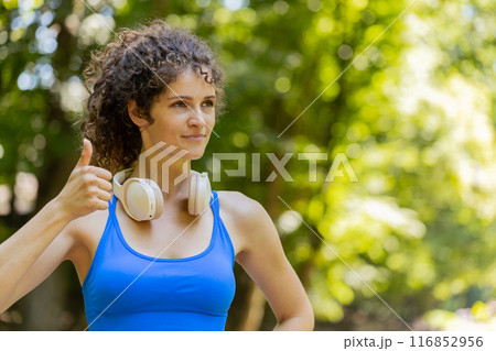 Athletic fit smiling runner girl, happy about marathon achievement showing thumb up like gesture 116852956
