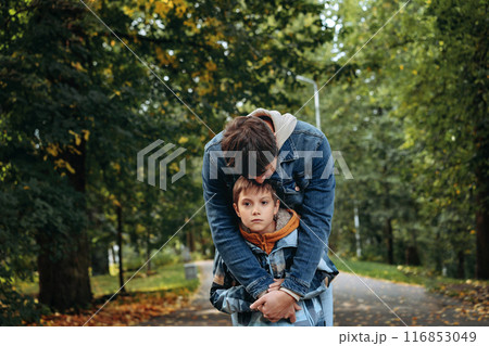 Caucasian man hugging his son in autumn park supporting sad boy 116853049