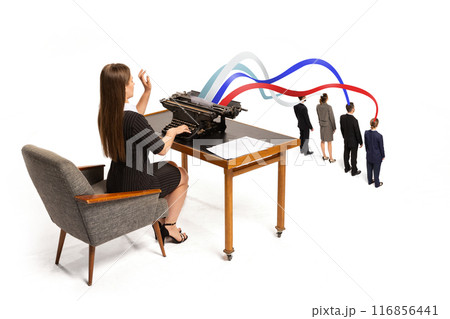 Woman types on vintage typewriter sending colorful streams, in colors of American flag, into heads of small professionals. 116856441