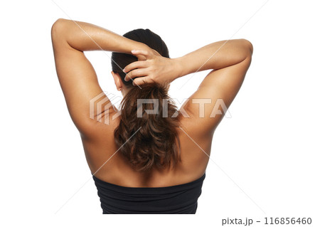 Woman shown from back, tying her long, wavy, with natural shine hair into ponytail against white studio background. Woman shown from back, tying her long, wavy, with natural shine hair into ponytail against white studio background. 116856460