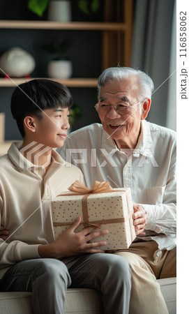 A son gives his father a gift, beautifully packaged in a box. Strong family ties 116858062